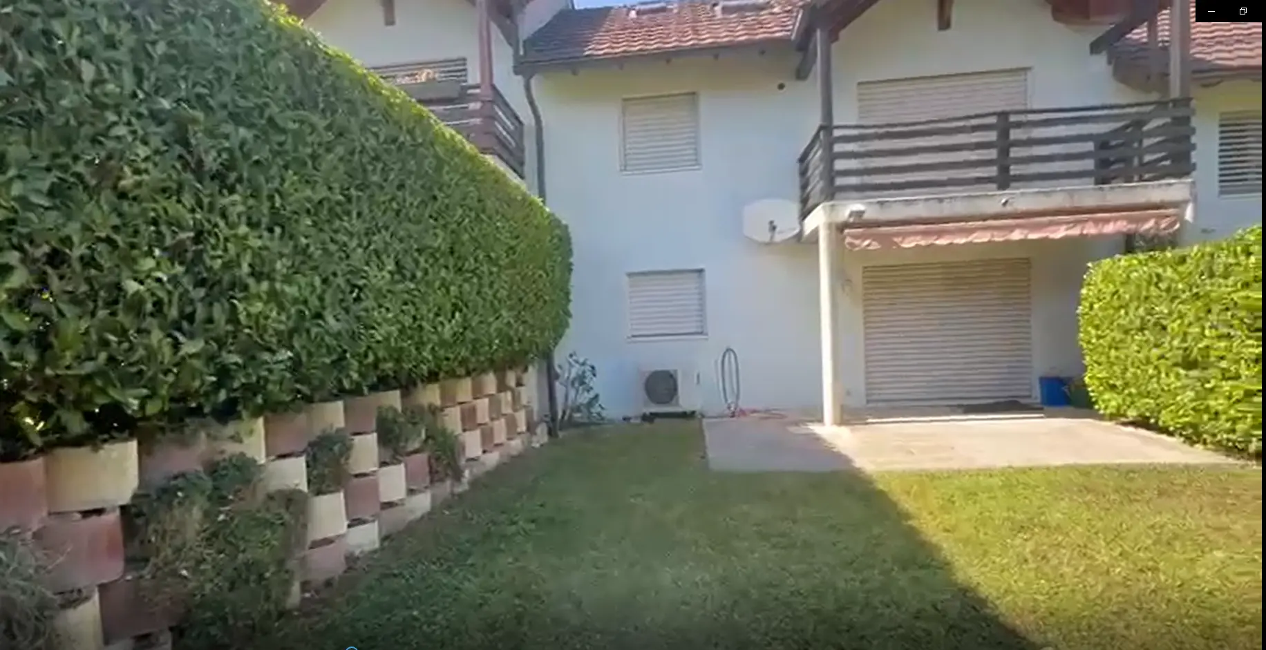 Pelouse et haie soignées devant une villa
